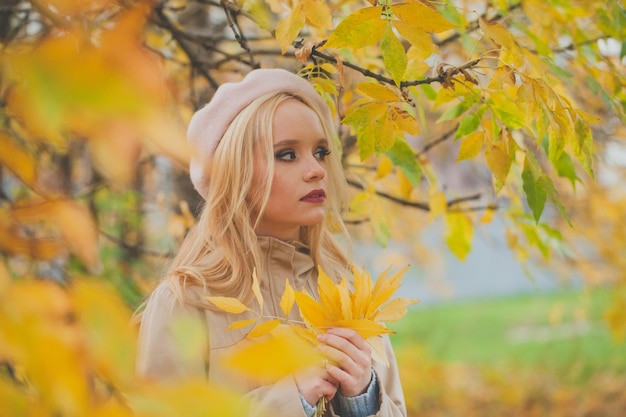 Mujer de otoño con hojas amarillas en el fondo de la naturaleza de otoño