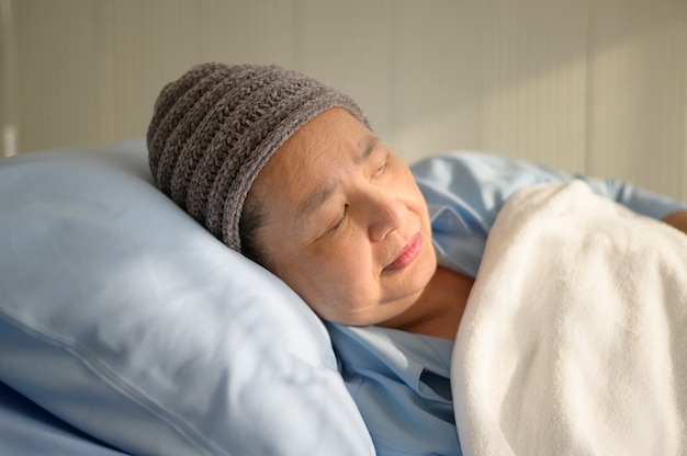 Una mujer paciente de cáncer asiática deprimida y desesperada con pañuelo en la cabeza en el hospital.