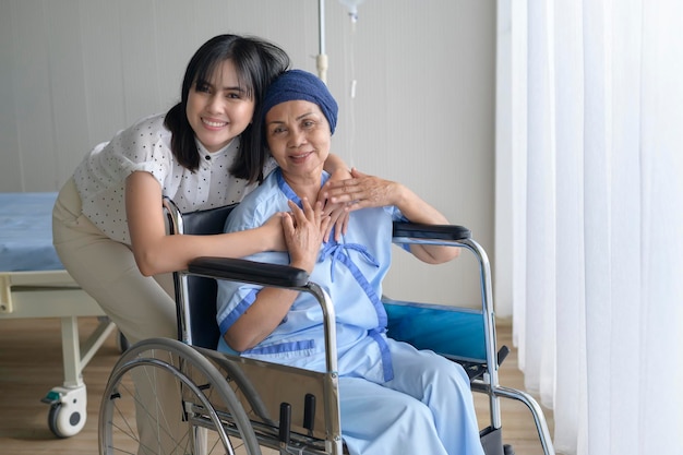 Mujer paciente con cáncer con pañuelo en la cabeza y su hija solidaria en el hospital