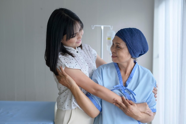 Mujer paciente con cáncer con pañuelo en la cabeza y su hija solidaria en el hospital
