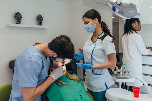 Mujer paciente en clínica dental siendo examinada por un dentista masculino