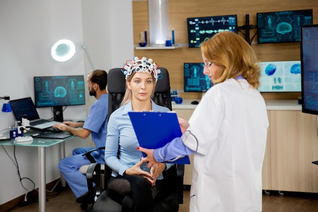 Mujer paciente escaneando su cerebro y mirando un portapapeles sosteniendo al médico en su mano