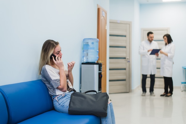 Mujer paciente hablando en el teléfono móvil en la sala de espera del hospital.