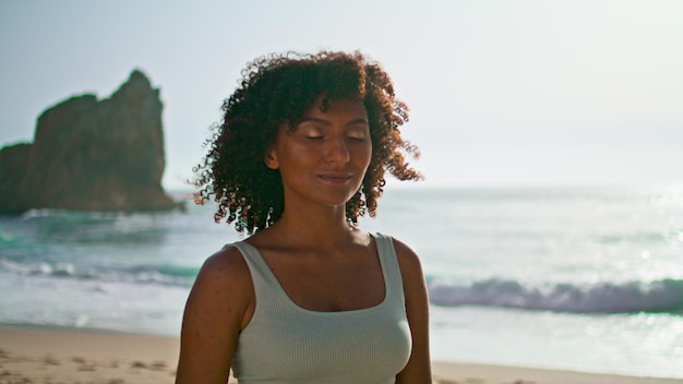Mujer pacífica meditando playa chica de cerca poniendo la mano en el pecho al amanecer.
