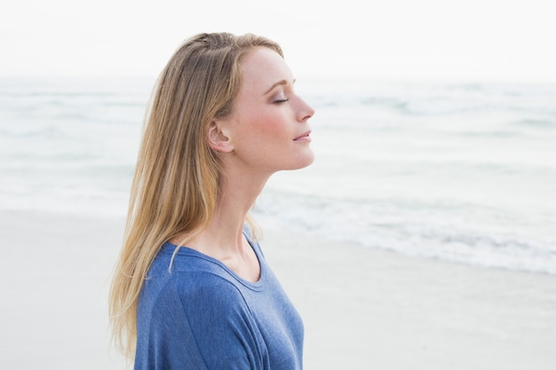 Mujer pacífica con los ojos cerrados en la playa