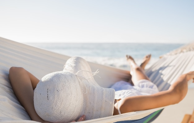 Mujer pacífica en sunhat descansando en hamaca