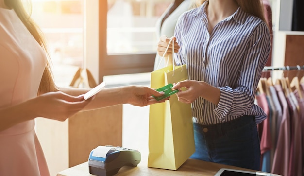 Mujer pagando con tarjeta de crédito para comprar en la sala de exposición de ropa. Concepto de transacciones financieras y no monetarias