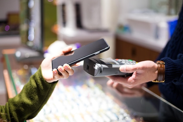 Mujer pagando con tecnología NFC en un teléfono inteligente en una tienda