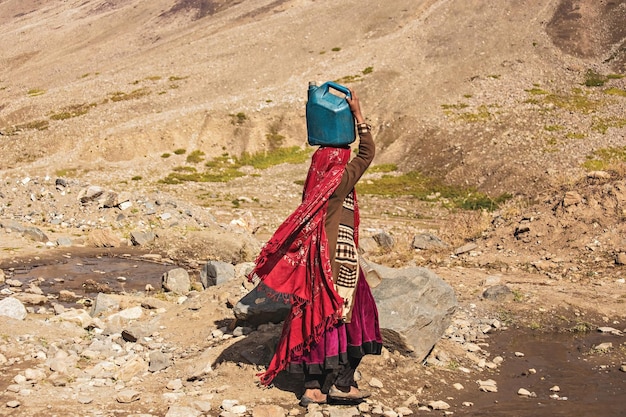 Mujer pakistaní con una jarra de agua en la cabeza en la aldea en el norte de Pakistán