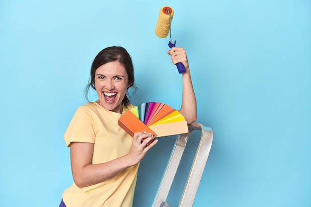 Mujer con paleta de colores pintando la pared en la escalera