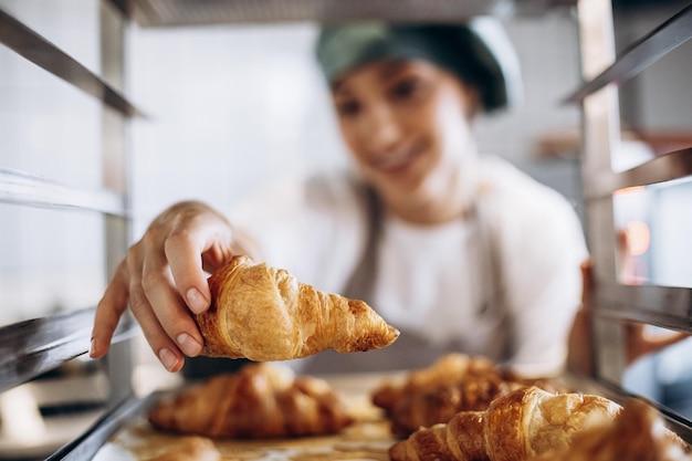 Mujer panadera en la cocina con croissant