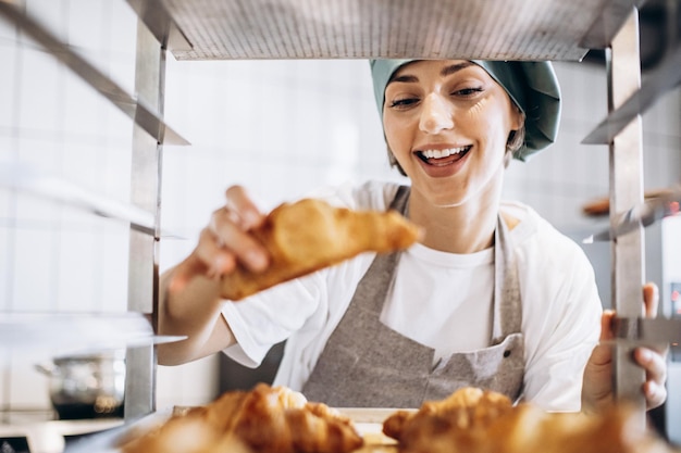 Mujer panadera en la cocina con croissant