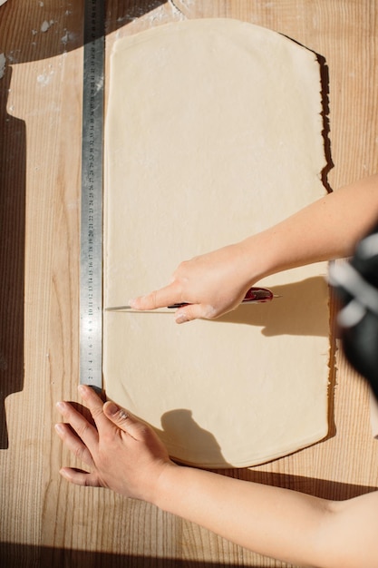 Mujer panadera corta la masa en triángulos para croissants Elaboración de croissants en la panadería