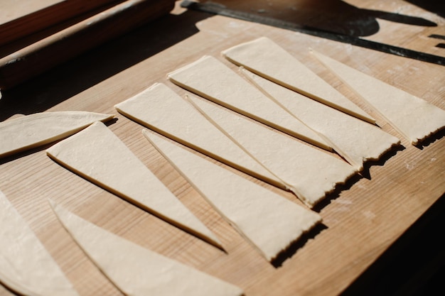 Mujer panadera corta la masa en triángulos para croissants Elaboración de croissants en la panadería