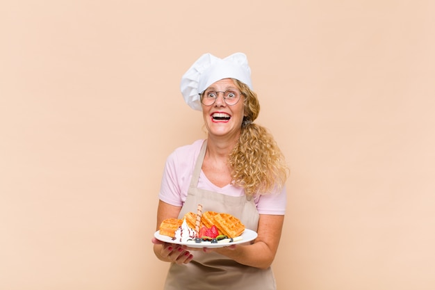 Mujer panadera de mediana edad cocinando gofres