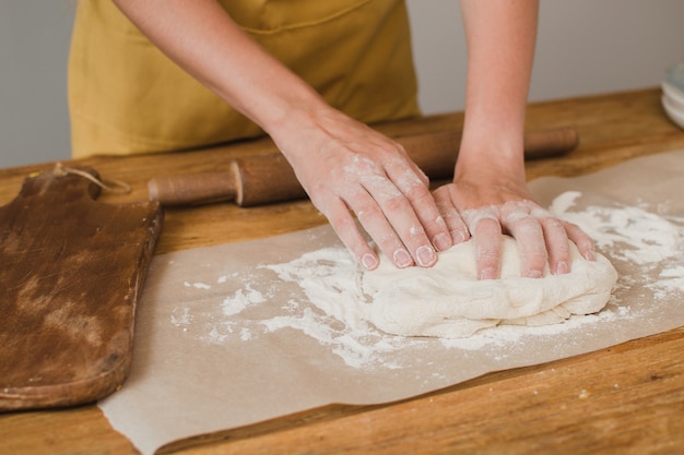 Una mujer panadera o pastelera amasa la masa. De cerca.