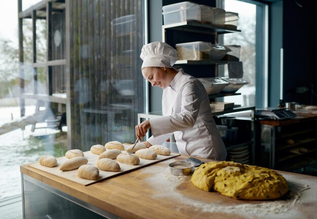 Mujer panadera con uniforme dedicada a hacer bollos de levadura tradicionales con queso