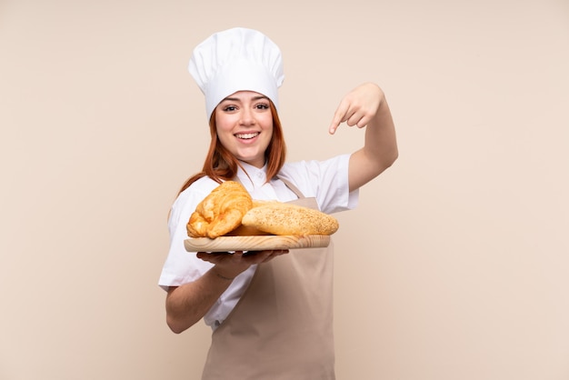 Mujer panadero sosteniendo una mesa con varios panes y apuntando