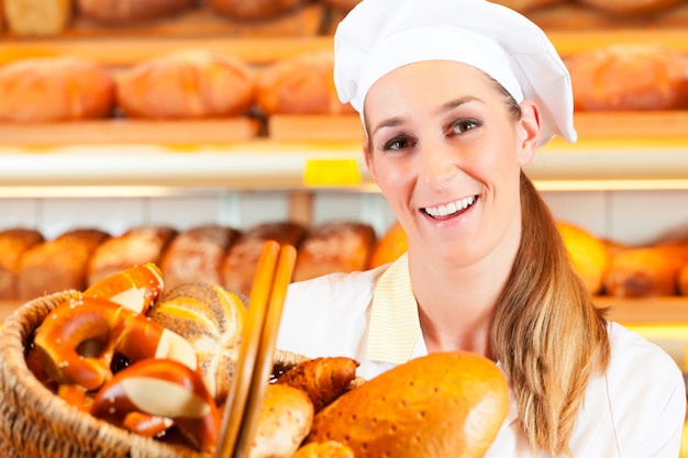 Mujer panadero vendiendo pan por canasta en panadería