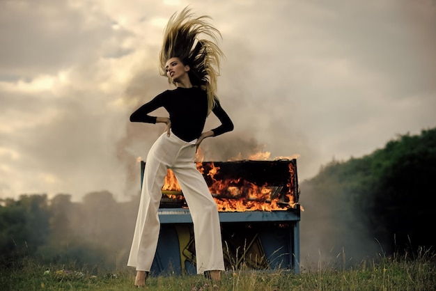 Mujer de pantalón blanco en el piano en llamas