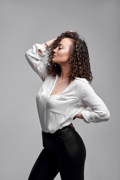 mujer de pantalón negro y camisa blanca. Retrato de moda de una joven mujer elegante. Retrato de moda con una joven modelo caucásica. Pelo RIZADO,