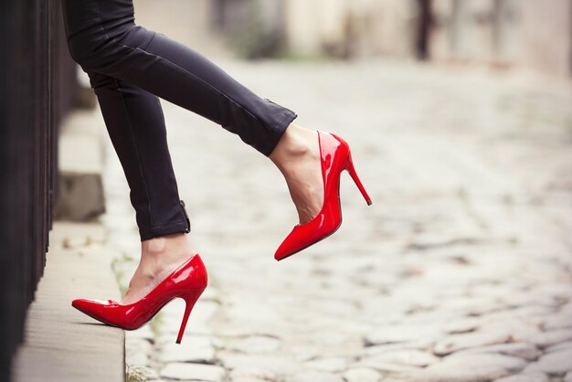 Foto mujer con pantalones de cuero negro y zapatos rojos de tacón alto en el casco antiguo