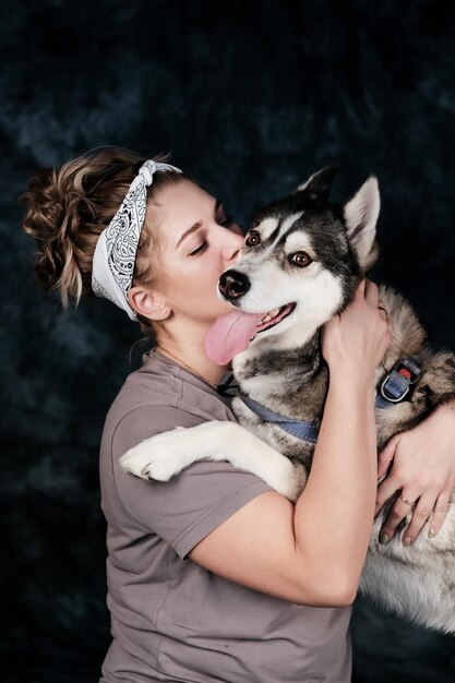 Una mujer con un pañuelo en la cabeza besando a un perro husky.