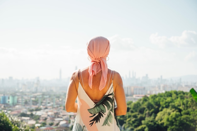 Mujer con pañuelo rosa mirando el horizonte. Concepto de cáncer