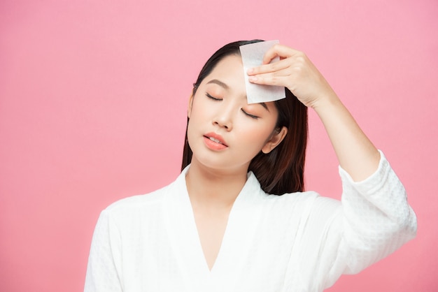 Foto mujer con papel secante de aceite facial. foto de mujer con maquillaje perfecto sobre fondo rosa. concepto de belleza