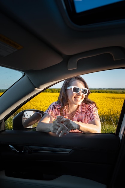 Mujer parada para disfrutar de la puesta de sol en el viaje en coche por carretera