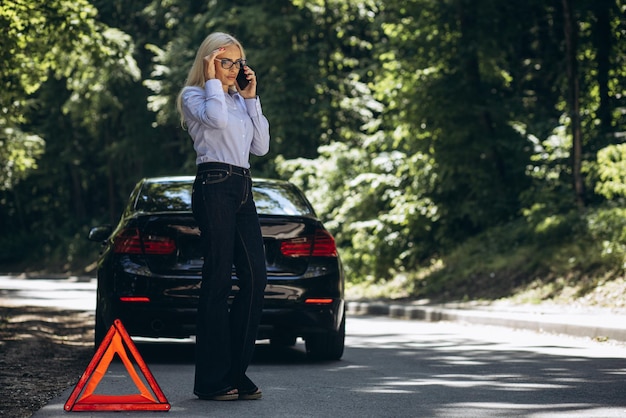 Mujer parada junto al auto debido a una avería