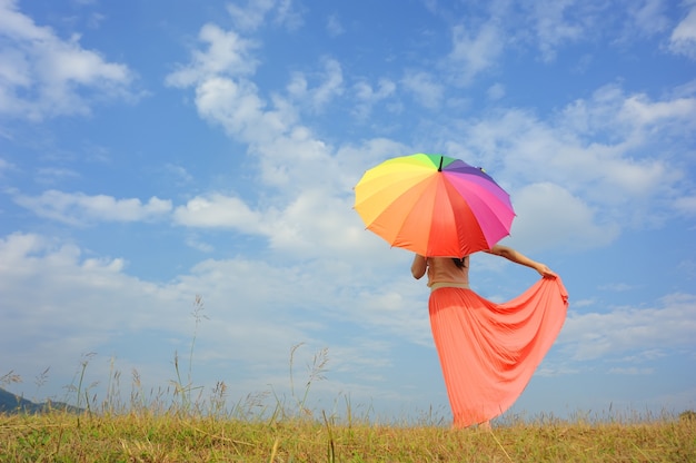 Mujer con paraguas de arco iris y cielo azul