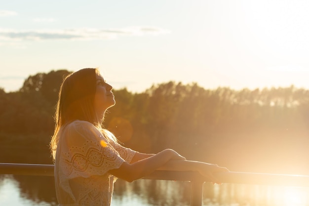 Foto mujer con paraguas contra el cielo durante la puesta de sol