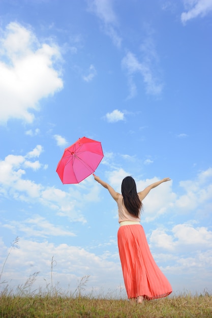 Mujer con paraguas rojo y cielo azul