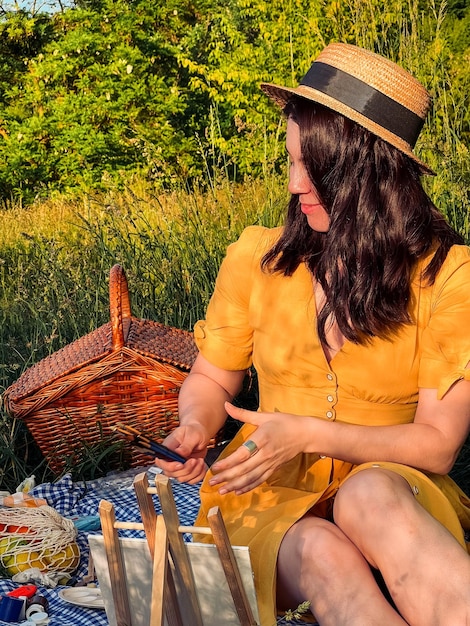 La mujer del paraíso de los pintores con un vestido amarillo y un sombrero crea arte durante un picnic