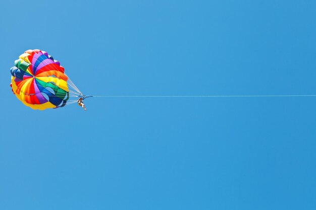 Mujer parakiting en paracaídas en cielo azul