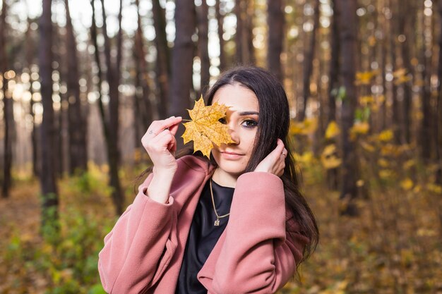 Mujer en el parque de otoño posando y sosteniendo la hoja