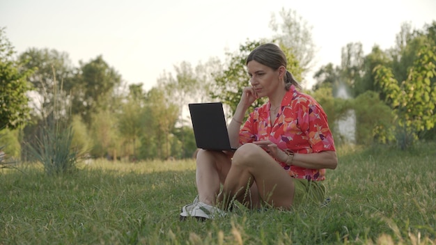 Mujer en el parque recibe capacitación en línea usando su computadora portátil