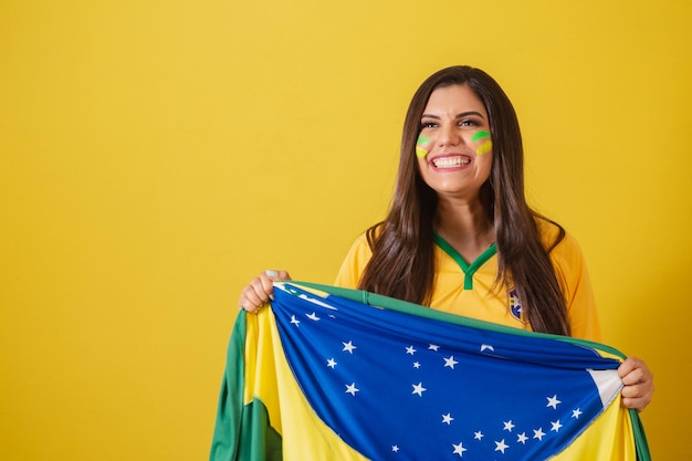 Mujer partidaria del campeonato mundial de fútbol de Brasil 2022 con bandera ondeando la victoria