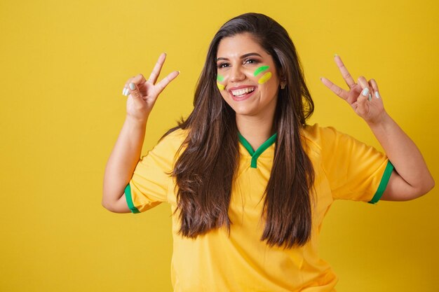 Mujer partidaria del campeonato mundial de fútbol de Brasil 2022 Con signo de paz y amor con los dedos