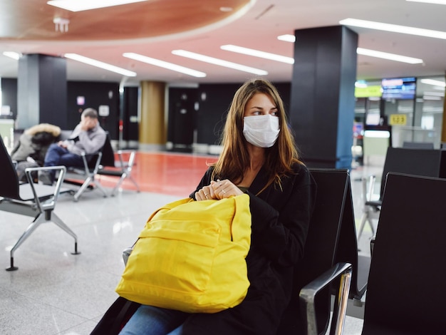 Foto mujer pasajero amarillo mochila aeropuerto esperando máscara médica