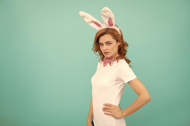 Mujer de Pascua con orejas de conejo sobre fondo azul.