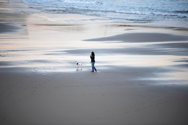 Mujer paseando a su perro en la playa