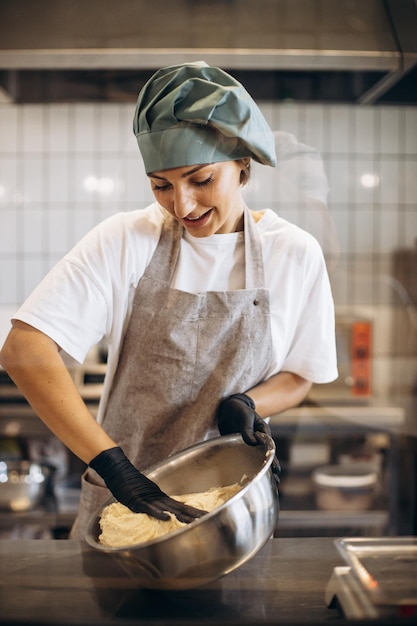 Mujer pastelera en la cocina haciendo masa para croissants