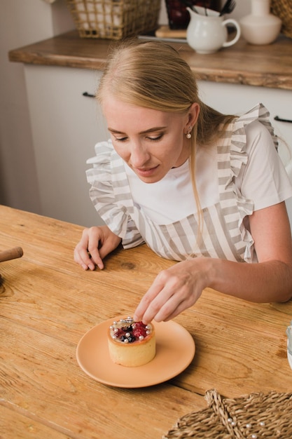 Mujer pastelera en delantal decora el postre