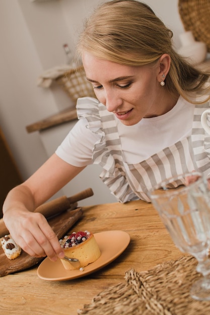 Mujer pastelera en delantal decora el postre