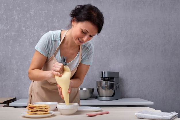 Foto la mujer pastelera prepara pastel de tartas y crema. proceso de elaboración de la torta.