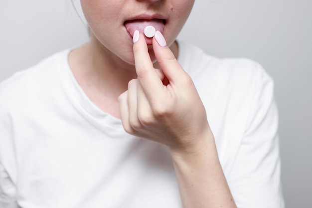 Una mujer con una pastilla en la lengua closeup medicina