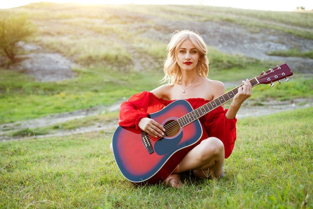 Mujer en pasto rojo con una guitarra roja