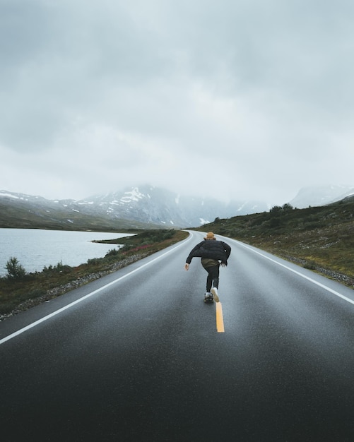 Mujer patinando en la carretera contra el cielo durante el tiempo de niebla